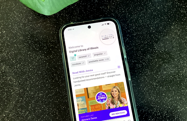 A smartphone on a black specked table top shows the home screen of the Libby app.